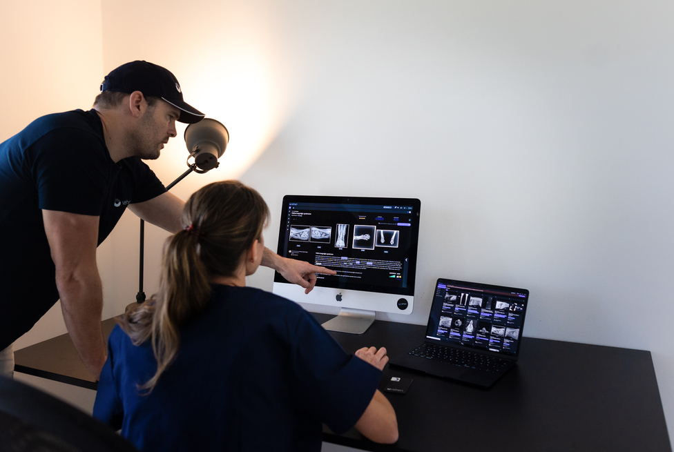Two veterinary imaging professionals reviewing a Veheri case report and radiographs.